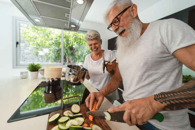 Retired couple cooking together in modern kitchen, reflecting property-focused lifestyle planning Retired couple cooking together in modern kitchen, reflecting property-focused lifestyle planning